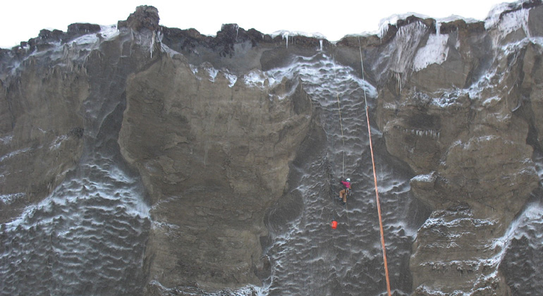 AWI | | CodyJohnson | Researchers are working at the yedoma cliff (35 meter high, 680 long) at the Itkillit river in Northern Alaska. Here one can see ice wedges next to frozen sediment pillars. The ice is up to 50 000 years old.