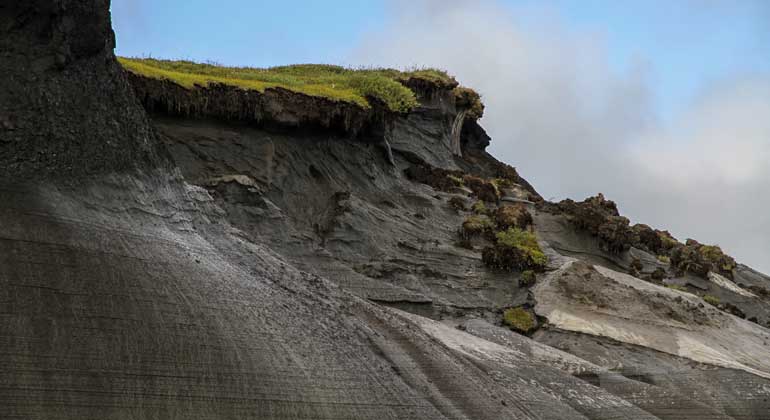 Alfred-Wegener-Institut (AWI) | Jaroslav Obu | Erodierende Steilküste der Herschel-Insel, Yukon Kanada Überall dort, wo das Eis im Boden taut, rutschen Grassoden, Humusschiht und Lockergestein als Schlammlawine Richtung Meer.Pro Jahr zieht sich die Küstenlinie so um mehrere Meter zurück.