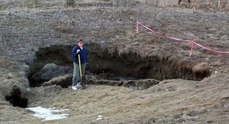 UAF | UAF researcher Vladimir Romanovsky poses near Fairbanks, Alaska in a place where permafrost has thawed, causing a surface disruption.