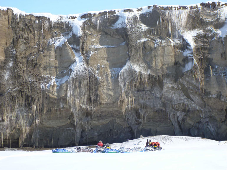 Guido Grosse, Alfred-Wegener-Institut | The about 30 m high Itkillik River exposure in the Yedoma permafrost deposits of North Alaska in winter provides an impressive sight for the US-German snow machine team (Ben Jones, Chris Arp, Ben Gaglioti, Guido Grosse) out there conducting thermokarst lake and permafrost studies in 2014.